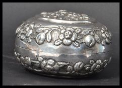 A 19th century Chinese silver (tested) lidded trinket pot cast in relief with flowers and leaves.