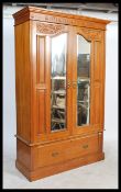 An Edwardian satin walnut single wardrobe being raised on a plinth drawer base with mirror glass