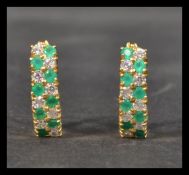 A pair of hallmarked 18ct gold earrings being set with green and white stones having lever backs.