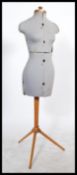 A vintage 20th century dress makers female mannequin bust raised on a tubular wooden tripod base.