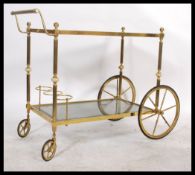 A retro style brass and glass retro two tier butlers drinks trolley with two large wheels to rear