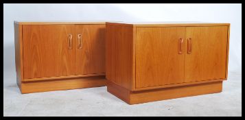 A pair of 1970's retro teak wood low sideboard - cabinets, each being raised on inset plinth bases