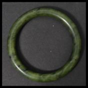 An early 20th century Chinese carved jade bangle of circular form in a deep green colour. Weighs
