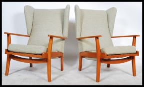 A 1970's retro vintage teak wood wingback three piece suite comprising of a pair of wingback