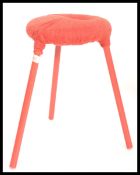 A vintage retro 20th century tripod stool raised on red painted tapering legs with woolen red