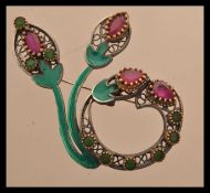 A sterling silver and enamel brooch in the form of a flower. Scrolled form with red and green