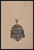 A sterling silver and rock crystal necklace pendant in the form of a Buddha with ruby panels.