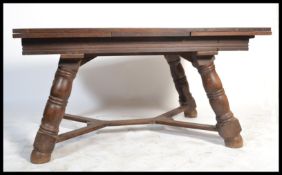 A large 1930's oak refectory dining table being raised on large angular legs united by stretchers