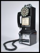 An American style contemporary coin operated wall telephone by Wild and Wolf having a ring dial
