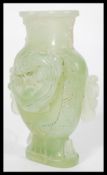 A Chinese jade vase raised on a pedestal base depicting dragons with twin dragon handles.