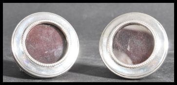 A pair of silver hallmarked miniature picture frames being easel backed. The frames of circular form