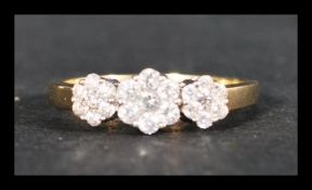 An 18ct gold and diamond triple cluster ring. Marked 18k tests 18ct gold. Traces of worn hallmark.