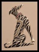 A sterling silver and enamel dog brooch having a ruby collar. Weighs 10 grams.