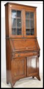 An early 20th Century Arts and Crafts oak student bureau bookcase having glazed bookcase over fall