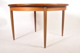 A retro 1960's teak wood G-Plan extending dining table of round form raised on tapering legs