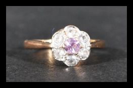 A hallmarked 9ct gold cluster ring having a central purple stone surrounded by white stones.