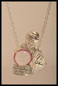 A silver plated large figural magnifying pendant in the form of a fortune teller with crystal ball.