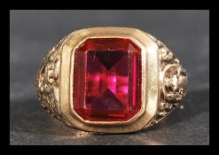 A hallmarked 9ct gold and ruby ring having a large central bezel set emerald cut  synthetic ruby