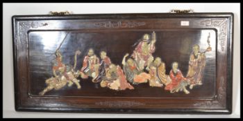 An early 20th century Japanese ebonised and lacquered shibiyama panel decorated in relief with