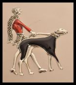 A sterling silver and enamel art deco brooch in the form of a lady walking her dog. Weighs 11