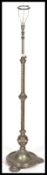 A polished metal rococo revival standard lamp being raised on a terraced base with pad feet and a