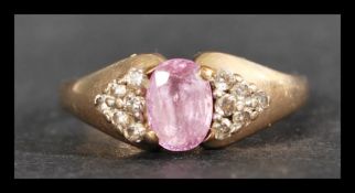 A hallmarked 9ct gold sapphire and diamond ring. Set with an oval mixed cut purple sapphire flanked