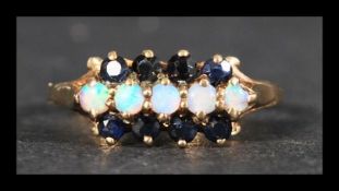 A hallmarked 9ct gold sapphire and opal ring being set with 5 opal cabochon and 8 blue sapphires.