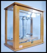 A set of vintage apothecary scales and weights, housed within a wooden and glass case, sliding front