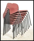 A set of 8 mid century / 1970's stacking chairs with composite red seats set over grey tubular metal