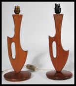 A pair of mid 20th century retro teak table lamps of angular sculptured form raised on circular