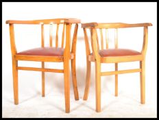 A pair of mid century beechwood elbow chairs - armchairs being raised on squared legs with panel