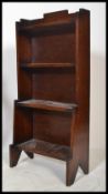 An early 20th Century oak Art Deco open waterfall bookcase of small proportions having three fixed