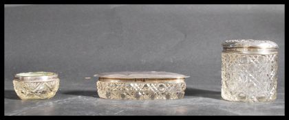 A group of three hallmarked silver cut glass pots to include a lidded cylindrical pot hallmarked for