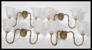 A set of four early 20th century brass twin wall sconces in the Georgian gaslight taste having