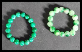 Two 20th century Chinese green jade bead bracelets. Each with green jade beads of spherical form.
