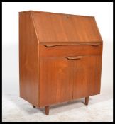 A 1970's retro teak wood Danish influence bureau being raised on stub legs with a series of