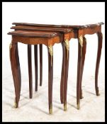 A 20th century kingwood and marquetry inlaid nest of tables raised on shaped legs with gilt metal