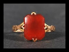 A 9ct gold ring having a prong set carnelian with stylised shoulders. Marked 9ct tests 9ct gold.