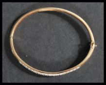 A 9ct gold and diamond bangle bracelet having illusion set diamonds to face with clip clasp and twin