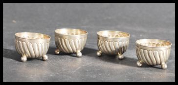 A set of four 19th century Victorian silver hallmarked table salts of reeded form raised on tripod