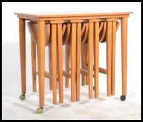 A 1970's retro teak wood quartetto nest of tables raised on turned legs with a series of tables to