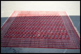 A large early 20th century Persian / Islamic carpet floor rug on red ground decorated with geometric