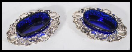 A pair of 19th century Victorian silver table salts of scrolled form having raised blue glass