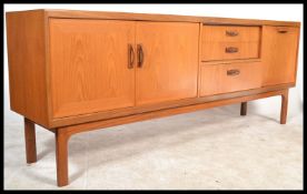 A 1970's retro G-Plan ' Sienna ' pattern large teak wood sideboard credenza being raised on turned