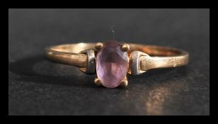 A 9ct gold ring set with an oval cut purple stone. Marked 9ct tests 9ct gold. Weight 1g. Size O.