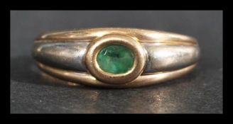 A hallmarked 9ct white and yellow gold ring with an oval cut bezel set emerald. Import mark for