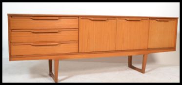 A 1970's / mid 20th century teak wood sideboard credenza being raised on tapering legs with a low