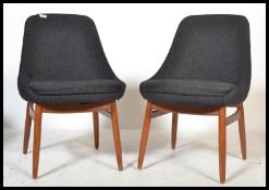 A pair of retro contemporary teak wood dining chairs on shaped tapering supports with black velour