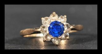 A hallmarked 9ct gold cluster ring having a central blue stone surrounded by white stones.