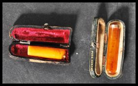 Two early 20th century amber cheroots in original leather cases one having a hallmarked 9ct gold